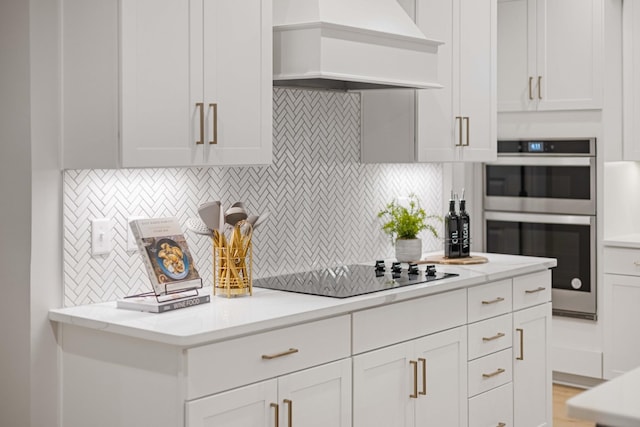 kitchen featuring white cabinets, black electric stovetop, custom exhaust hood, double oven, and backsplash