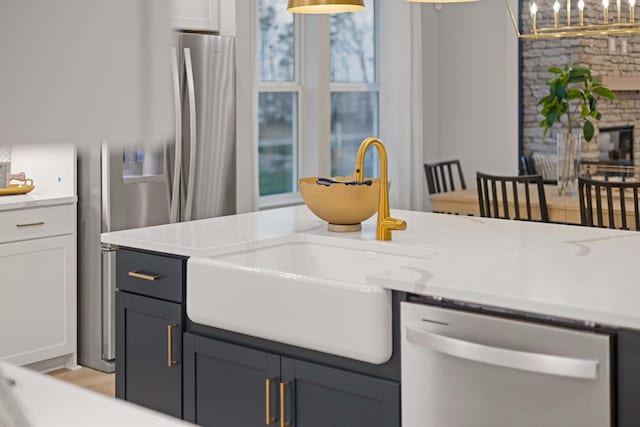 kitchen with dishwasher, hanging light fixtures, a glass covered fireplace, and a sink