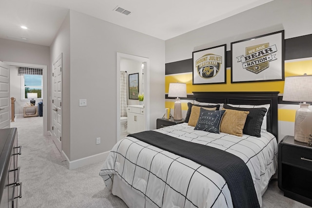 carpeted bedroom featuring visible vents, baseboards, and ensuite bathroom