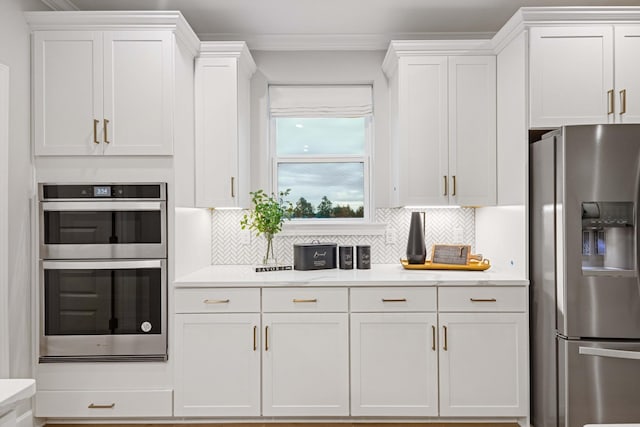 kitchen featuring stainless steel appliances, white cabinetry, and decorative backsplash