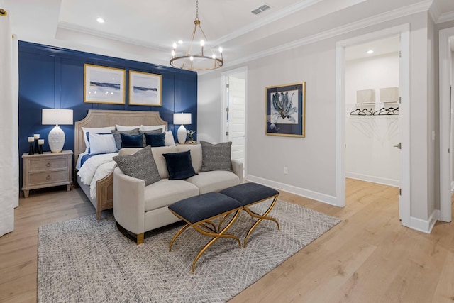 bedroom featuring light wood-type flooring, a tray ceiling, visible vents, and crown molding