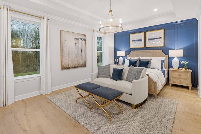 bedroom with light wood finished floors, a tray ceiling, and a notable chandelier