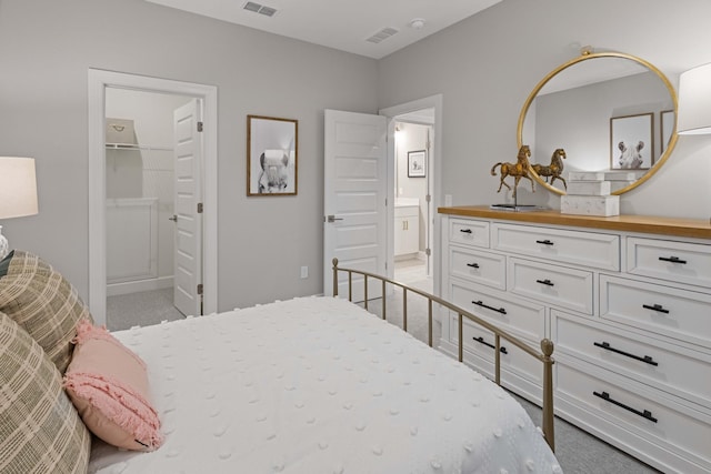 carpeted bedroom with visible vents and ensuite bath