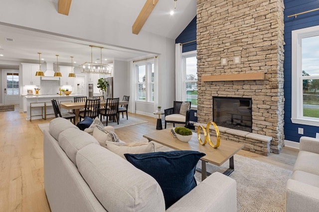 living room featuring light wood-style floors, beam ceiling, a healthy amount of sunlight, and a fireplace