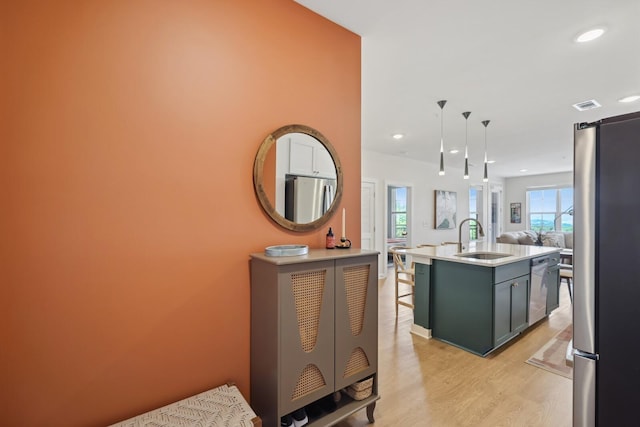 kitchen featuring visible vents, appliances with stainless steel finishes, open floor plan, light wood-style floors, and a sink