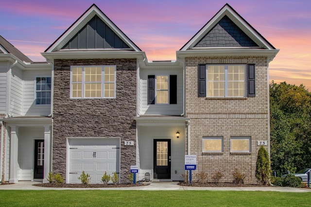 view of front of home featuring a garage, stone siding, a front lawn, and board and batten siding