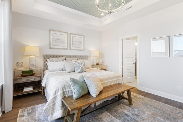 bedroom with baseboards, a tray ceiling, wood finished floors, and a notable chandelier