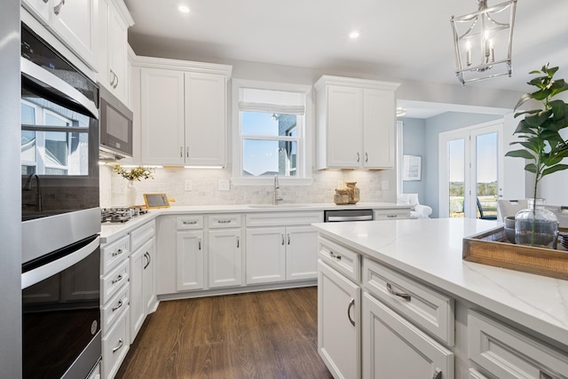 kitchen with stainless steel appliances, a wealth of natural light, white cabinets, and a sink