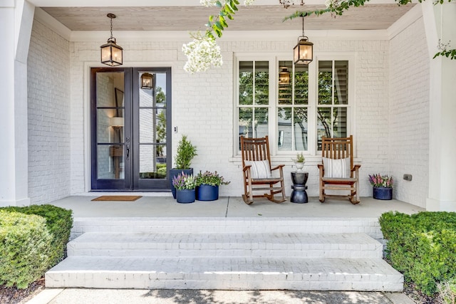 doorway to property featuring a porch and brick siding