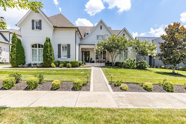 french country inspired facade with a front lawn and brick siding