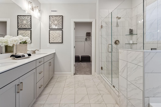 bathroom with marble finish floor, a sink, a walk in closet, and a shower stall