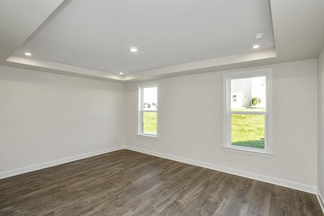 unfurnished room featuring baseboards, a raised ceiling, and dark wood-style flooring