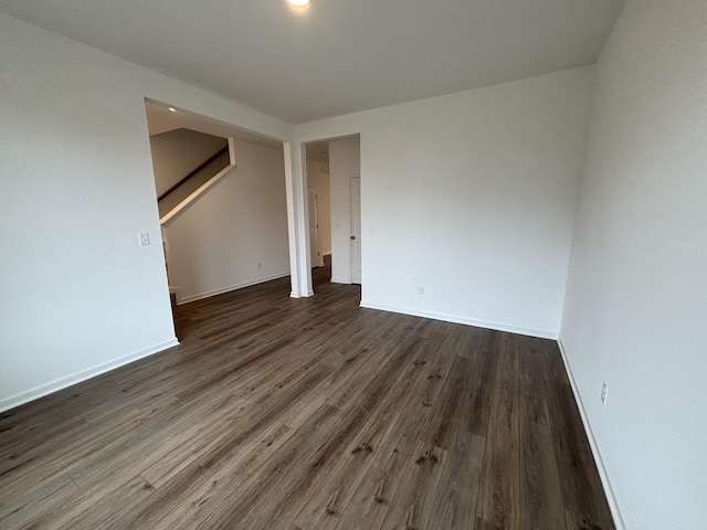 spare room featuring stairway, wood finished floors, and baseboards