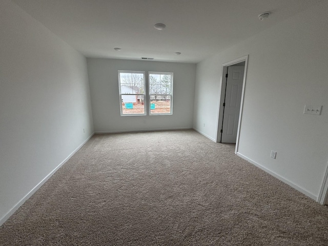 spare room with baseboards and light colored carpet