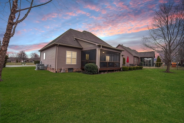 rear view of property featuring roof with shingles, a lawn, cooling unit, and a sunroom