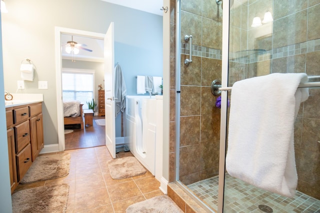 ensuite bathroom featuring a ceiling fan, connected bathroom, a shower stall, vanity, and tile patterned flooring