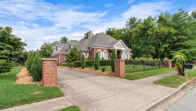 view of front of property with a fenced front yard, brick siding, a chimney, and a front lawn