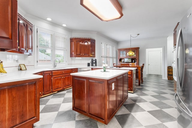 kitchen with light countertops, appliances with stainless steel finishes, a kitchen island, a sink, and tile patterned floors