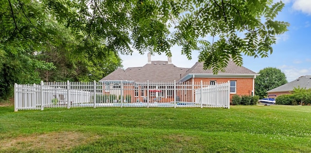 rear view of house with brick siding, a lawn, and fence