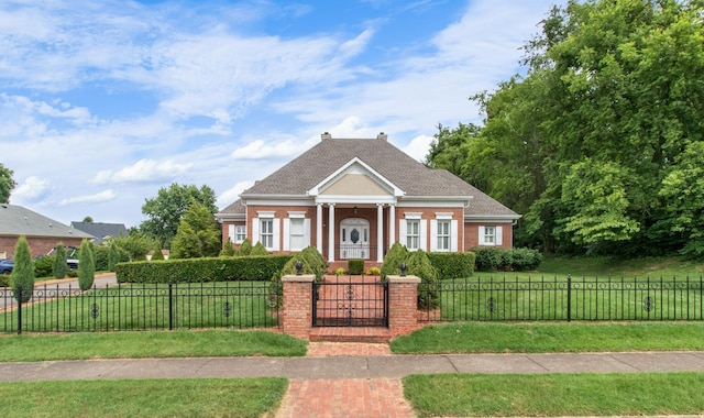 neoclassical home with a fenced front yard, a chimney, a front lawn, and brick siding