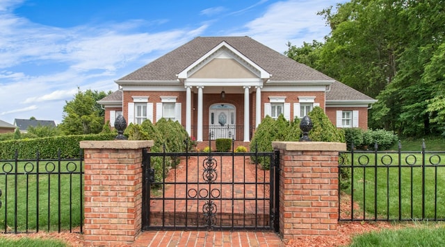 greek revival inspired property featuring a fenced front yard, roof with shingles, a front lawn, and brick siding