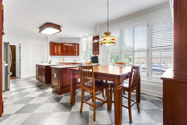 dining room featuring baseboards, crown molding, and light floors