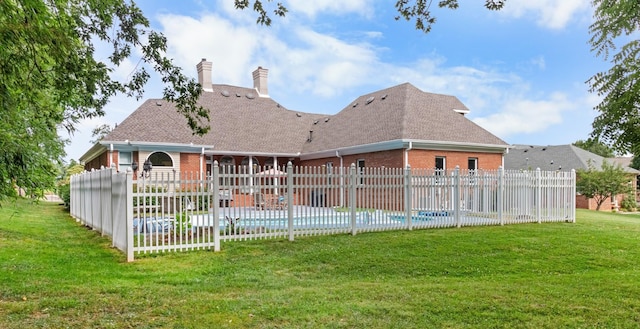 back of property featuring a fenced in pool, brick siding, a yard, a chimney, and fence