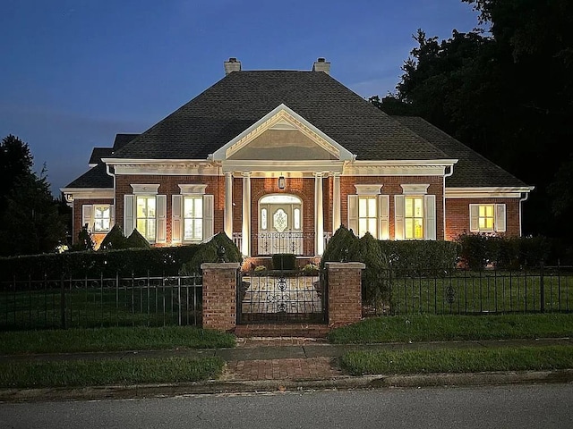 neoclassical home featuring brick siding, a fenced front yard, and a front lawn