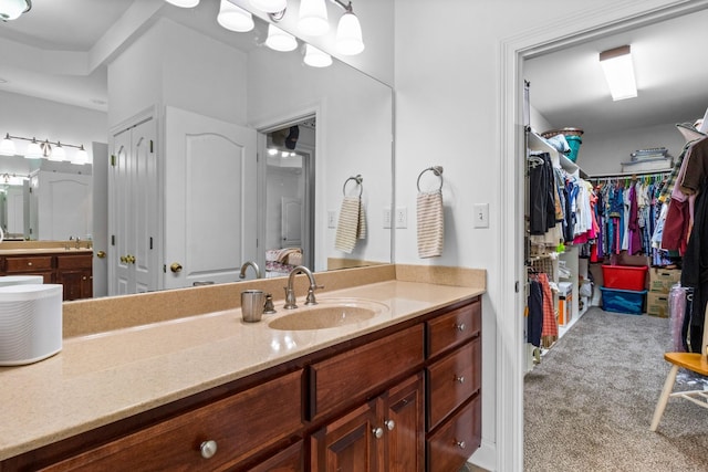 bathroom with a walk in closet and vanity