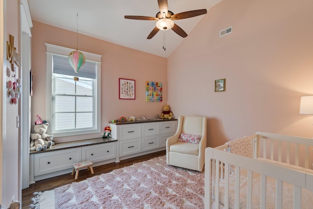 bedroom featuring dark wood finished floors, lofted ceiling, visible vents, a ceiling fan, and a nursery area