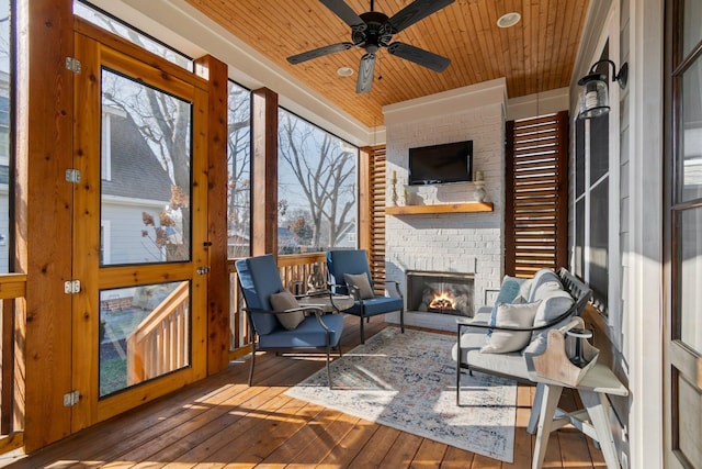 sunroom featuring wooden ceiling, a fireplace, and a ceiling fan