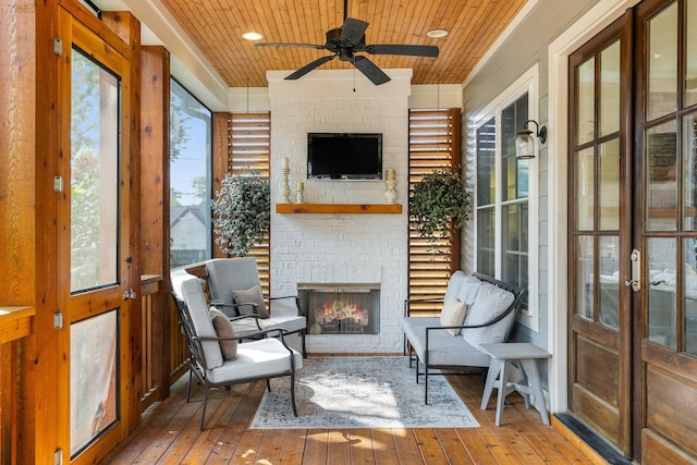 sunroom / solarium featuring wooden ceiling, an outdoor brick fireplace, and a ceiling fan