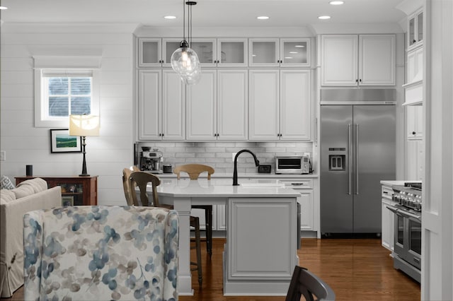 kitchen with premium appliances, dark wood-type flooring, a sink, and white cabinets