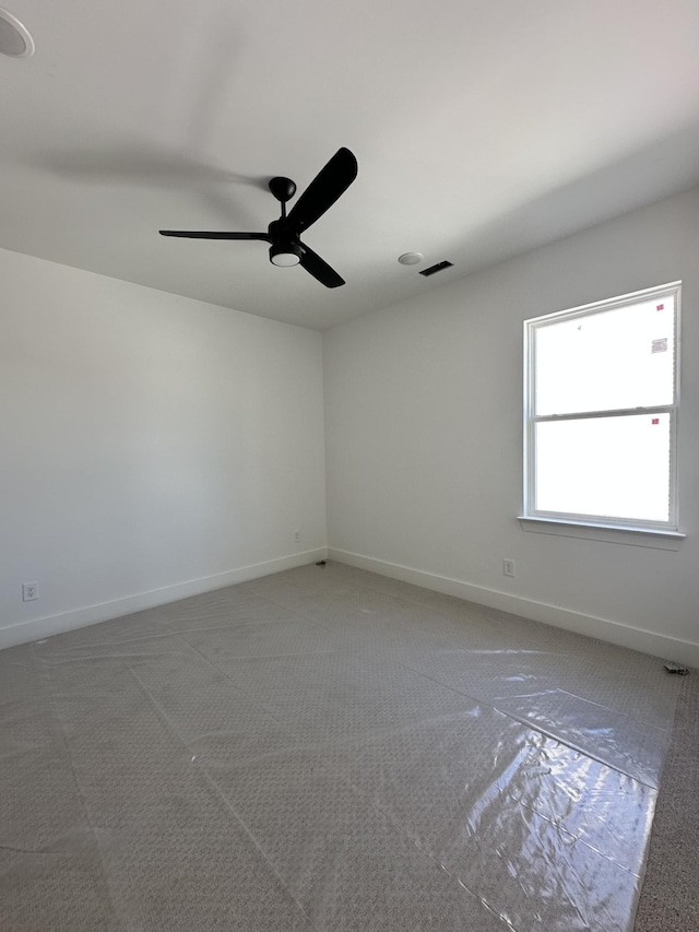 carpeted spare room featuring visible vents, baseboards, and a ceiling fan