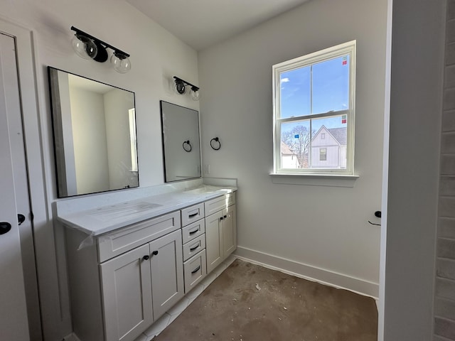 bathroom with concrete flooring, double vanity, a sink, and baseboards