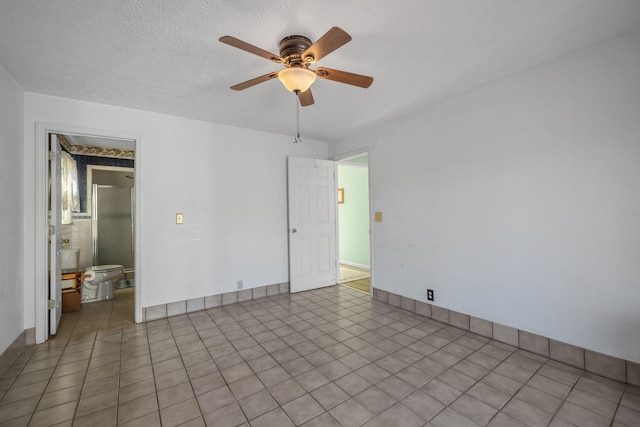 spare room with baseboards, a ceiling fan, and a textured ceiling