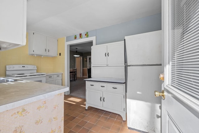 kitchen with backsplash, white cabinetry, and electric range