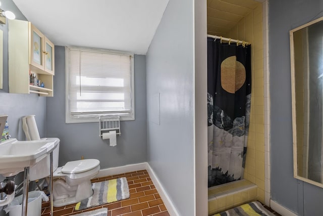 bathroom featuring a stall shower, toilet, and baseboards