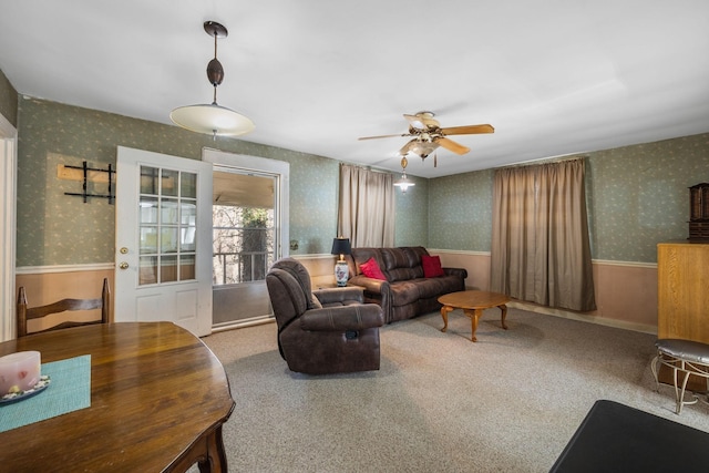 living room with a ceiling fan, a wainscoted wall, carpet flooring, and wallpapered walls