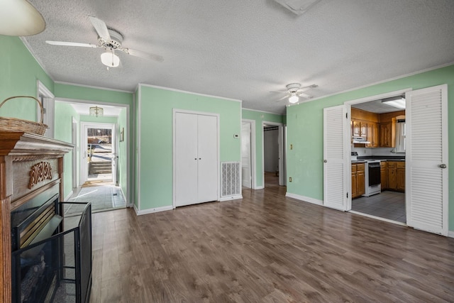 unfurnished living room featuring ornamental molding, a ceiling fan, a textured ceiling, and wood finished floors