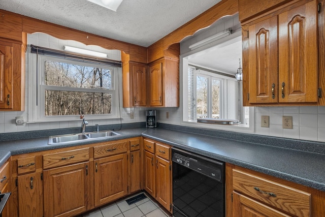 kitchen featuring dishwasher, dark countertops, a sink, and brown cabinets