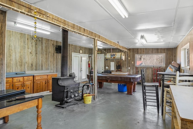 below grade area featuring pool table, wood walls, and a wood stove