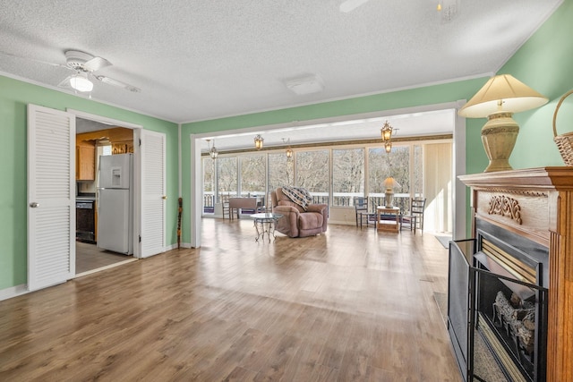 living room featuring a fireplace, a textured ceiling, baseboards, and wood finished floors