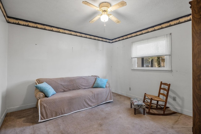 living area with a ceiling fan, a textured ceiling, baseboards, and carpet flooring