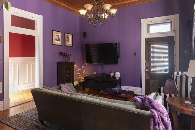 living room with ornamental molding, a chandelier, and wood finished floors