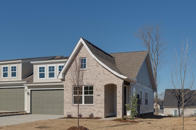 view of front of home featuring a garage, brick siding, driveway, and a shingled roof