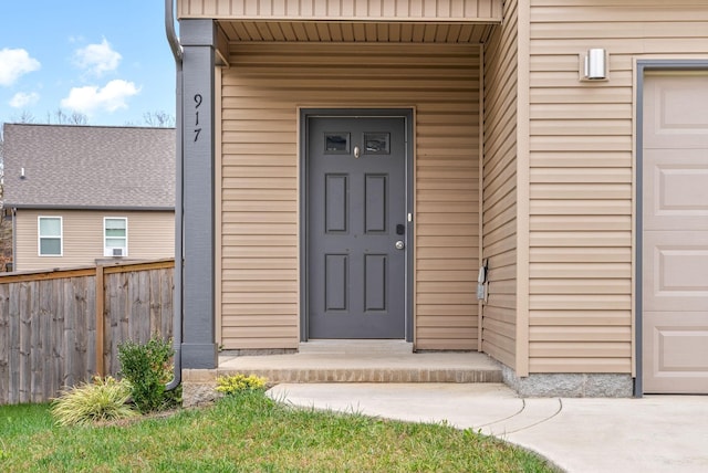 doorway to property featuring a garage and fence