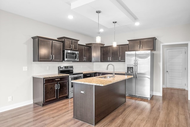 kitchen with light stone countertops, a sink, dark brown cabinets, appliances with stainless steel finishes, and decorative backsplash