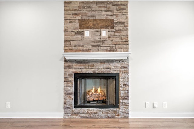 details featuring a lit fireplace, baseboards, and wood finished floors