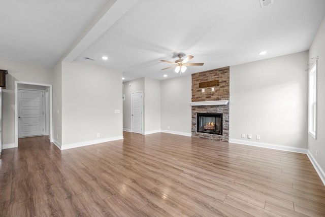 unfurnished living room featuring light wood finished floors, baseboards, a ceiling fan, a stone fireplace, and recessed lighting